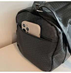 Dettaglio tasca laterale con cerniera di borsa da viaggio intrecciata nera con cellulare