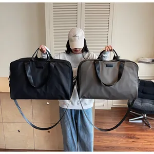Large capacity waterproof travel bags in black and grey held by a model for scale.