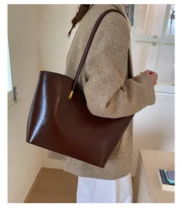 Vue détaillée d'un grand sac fourre-tout marron foncé brillant avec un manteau