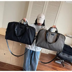 Woman holding large black and khaki waterproof travel bags showing stylish color options