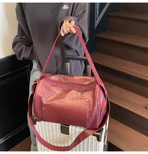 Primo piano della trama intrecciata bordeaux di una versatile borsa da viaggio.