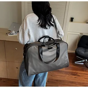 Large grey travel bag for women shown on model's shoulder for size comparison