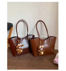 Deux sacs cabas marron élégants avec d'adorables porte-clés ours dans un décor cosy.
