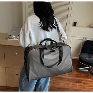Female model carrying a large grey waterproof travel duffel bag in a lifestyle setting