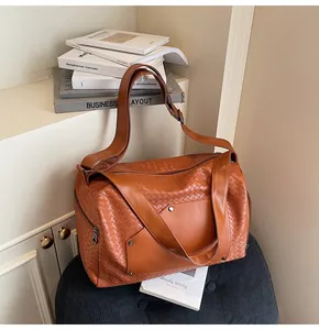 Primo piano di borsa sportiva intrecciata marrone con cinghie multifunzionali in stanza