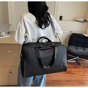 Detailed view of a black large capacity travel bag worn by a model in a modern office