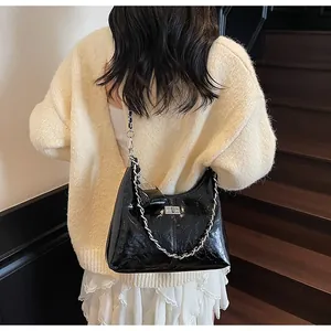 Stylish black glossy crinkled leather shoulder bag with silver chain strap on model