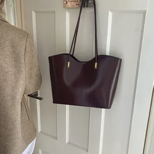 Grand sac cabas élégant en cuir brillant bordeaux avec détails dorés minimalistes