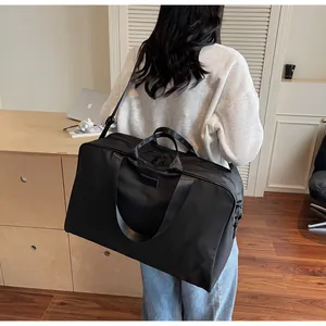 Rear view of a person carrying a spacious black travel duffle bag in a minimalist room