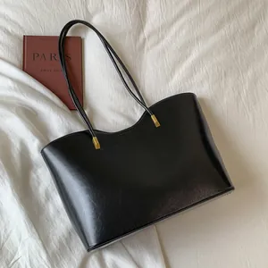 Grand sac cabas noir tendance avec détails dorés sur fond de tissu blanc épuré