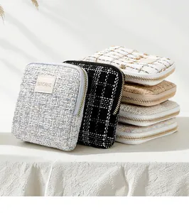 Detailed macro view of tweed jewelry storage pouches with gold zippers and labels.