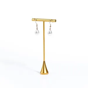 Goldener T-Ständer für Schmuck mit eleganten Perlenohrringen vor weißem Hintergrund
