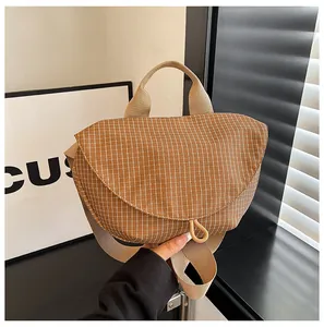 Vista detallada del bolso bandolera de lona a cuadros marrones con correa ancha beige