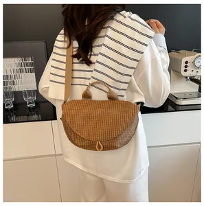 Detalle trasero de un bolso bandolera de lona a cuadros marrones sobre una camisa blanca