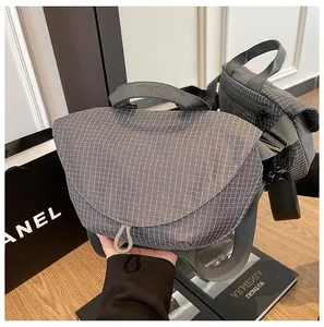 Detalle de un bolso bandolera informal a cuadros grises con cierre magnético.