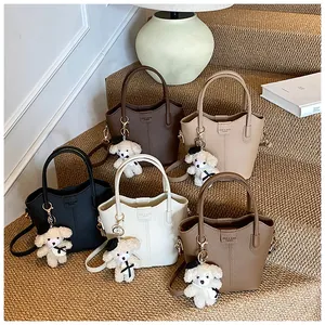 Macro detail of textured bucket bags in five colors with adorable plush dog charms.