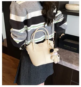 Chic off-white textured bucket bag worn by model with cute bear charm