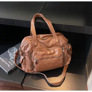 Close-up of vintage brown PU leather handbag with multiple functional zipper pockets