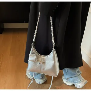 Close-up of a trendy silver metallic hobo bag on model with elegant chain strap