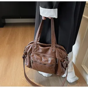Vintage brown PU leather tote bag with multiple pockets held in a lifestyle setting.