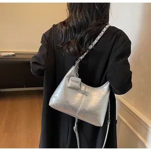 Detailed view of a stylish silver metallic hobo bag with chain strap and charm
