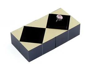 Vista detallada de una caja de anillo geométrica negra y dorada estilo cubo de Rubik para bodas