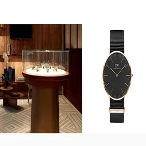 Κλασικό ρολόι Daniel Wellington με μαύρο καντράν και λουράκι νάιλον δίπλα σε πολυτελή βιτρίνα