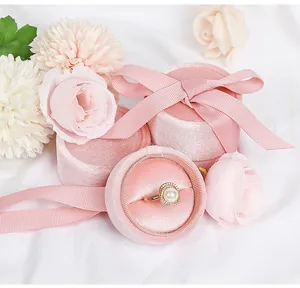 Detail shot of a pink velvet cylindrical jewelry box with a ribbon and pearl ring