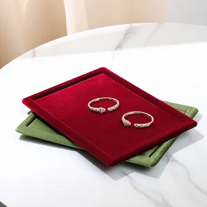 Luxurious red and green velvet jewelry display trays on a premium marble surface