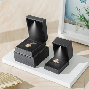 Elegant black LED lit jewelry box set for rings and necklaces on white display platform