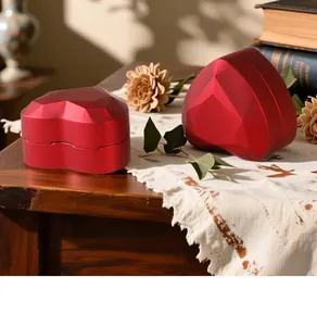 Elegant red heart-shaped jewelry box with geometric facets on a rustic wooden table