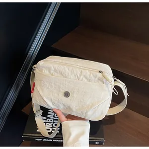Detailed view of cream nylon crossbody bag with textured fabric and wide shoulder strap