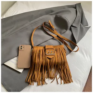 Vintage brown suede fringed crossbody bag with silver buckle shown on a gray blazer.