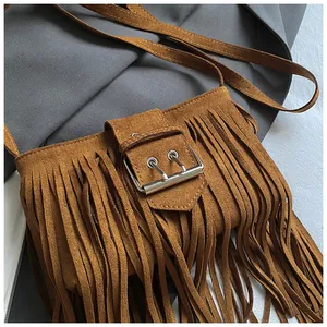 Close-up of vintage brown suede tassel saddle bag with fringe detail and metal buckle.