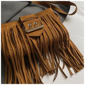 Close-up detail of a retro brown suede fringe saddle bag with stylish metal buckle