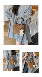 Detailed view of a stylish brown textured bucket bag featuring a cute plush bear charm