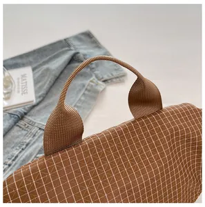 Primer plano de bolso de lona marrón a cuadros con asa de nailon tejida resistente.