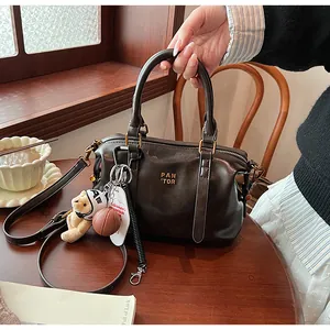 Vintage dunkelbraune Boston Tasche auf Holztisch mit Anhängern und Handmodell.