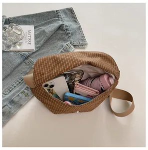 Vista detallada del interior de un bolso bandolera de lona a cuadros marrones con espacio