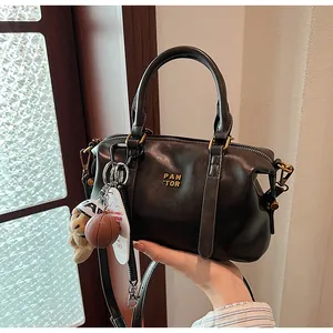 Detailansicht einer schwarzen Vintage-Boston-Tasche mit dekorativen Anhängern in der Hand