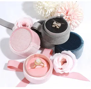 Premium cylindrical velvet jewelry boxes in pink, grey and teal with elegant ribbon detail.