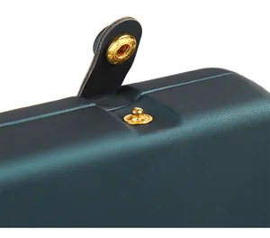 Detailed macro shot of the golden snap button on a dark teal leather jewelry box