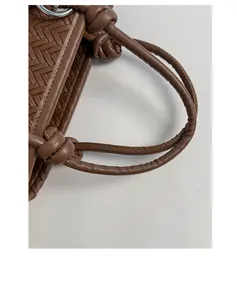 Detailaufnahme der Flechtstruktur und des geknoteten Griffs einer braunen Tasche