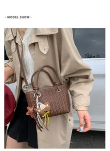 Braune Handtasche mit Webstruktur und Bärenanhänger in einer stilvollen Straßenansicht