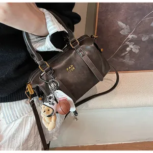 Detailansicht der braunen Boston-Tasche aus Leder mit Bären- und Basketballanhängern