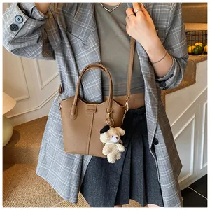 Brown textured leather bucket bag with a cute teddy bear charm on a plaid blazer outfit