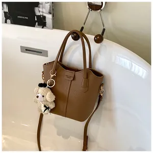 Detailed view of a brown textured leather bucket bag with a cute bear charm