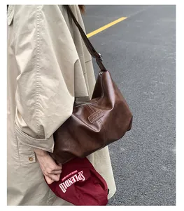 Close-up view of a vintage brown pleated hobo shoulder bag worn with a beige trench coat