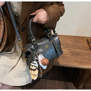 Detailansicht der schwarzen Boston-Tasche mit Plüschbären- und Basketball-Anhänger