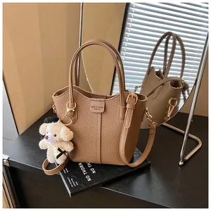 Elegant brown pebbled leather bucket bag with cute bear charm detail and gold hardware